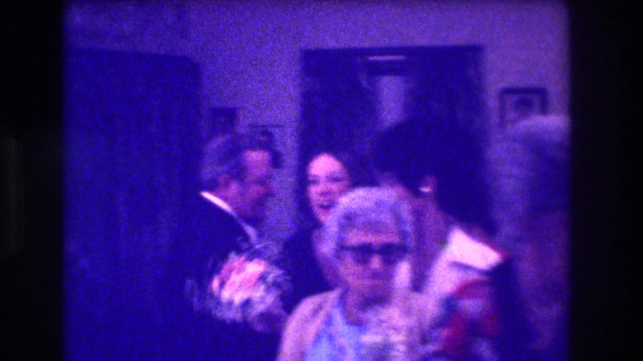 Medford, New Jersey, 1973 frame with a bouquet-holding woman among guests in a private interior, seen through heavy blue film cast.