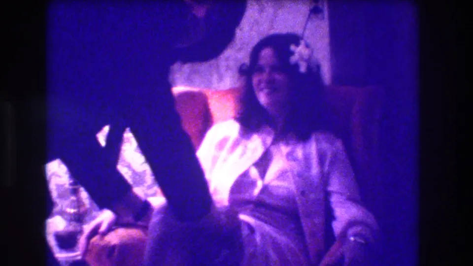 1973 Medford, New Jersey frame showing the bride smiling while the suited man reaches toward the garter area.