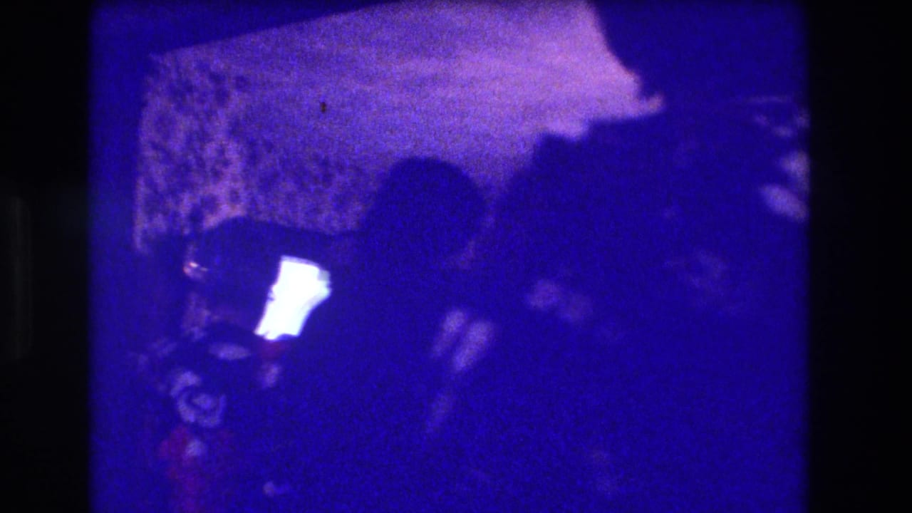 Dim group of party guests in silhouette with a bright light source at left.