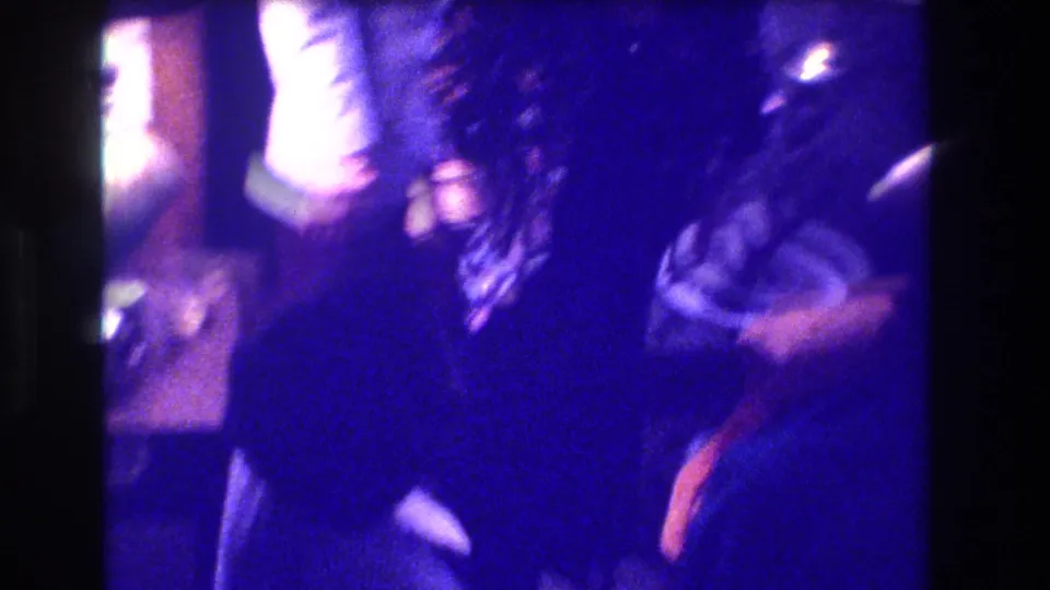 Motion-blurred closing frame of a person in dark clothing in a private home interior; typical handheld 8mm end-of-clip camera movement.