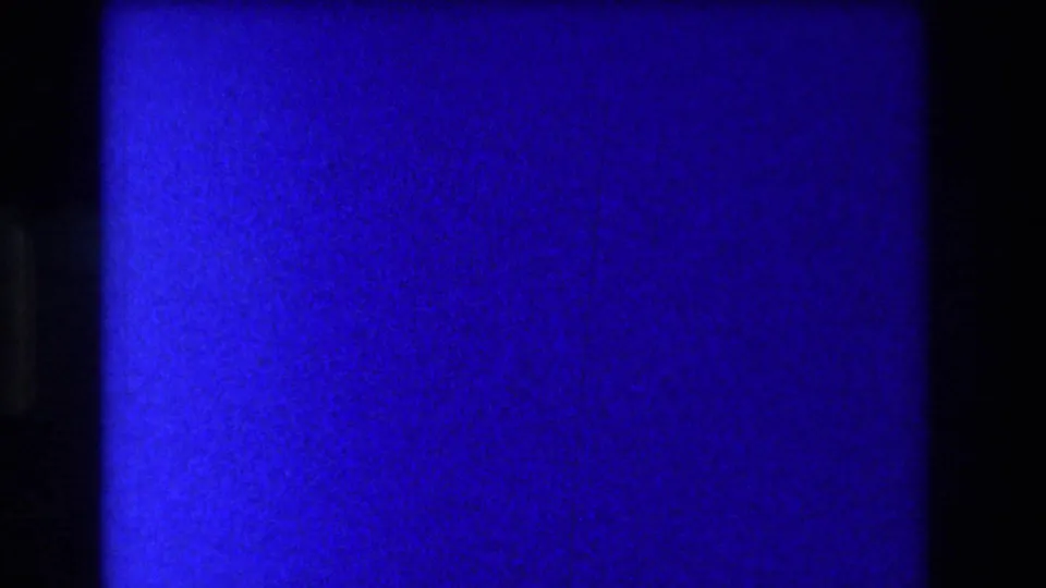 Deep blue color-shifted 8mm frame with faint dark silhouette at right edge — severe emulsion color shift consistent with aged 1973 home movie stock.