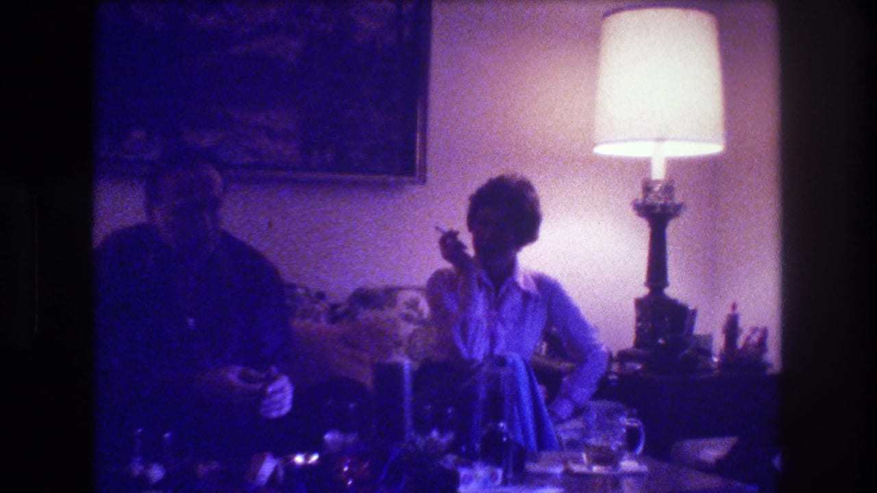 Woman smoking on a couch while a man sits beside her in low light.