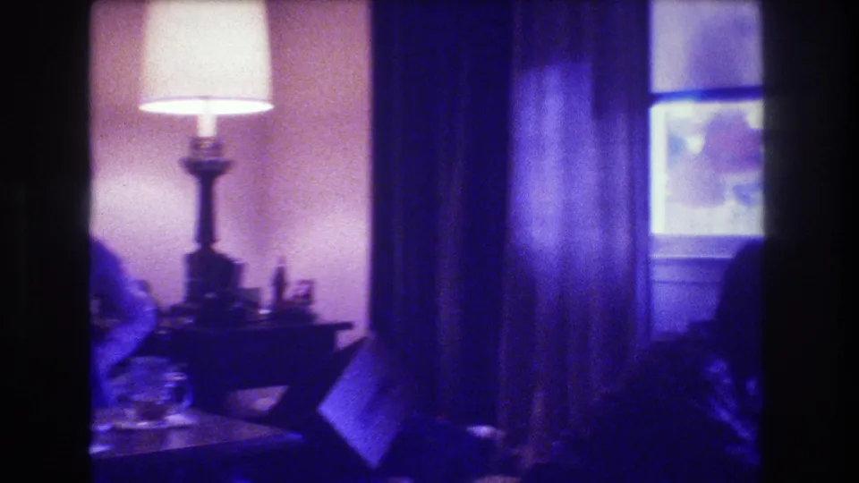 The final frame shifts toward the room, showing the glowing lamp, curtains, tabletop objects, and only part of the seated woman at the left edge of the Medford home interior.