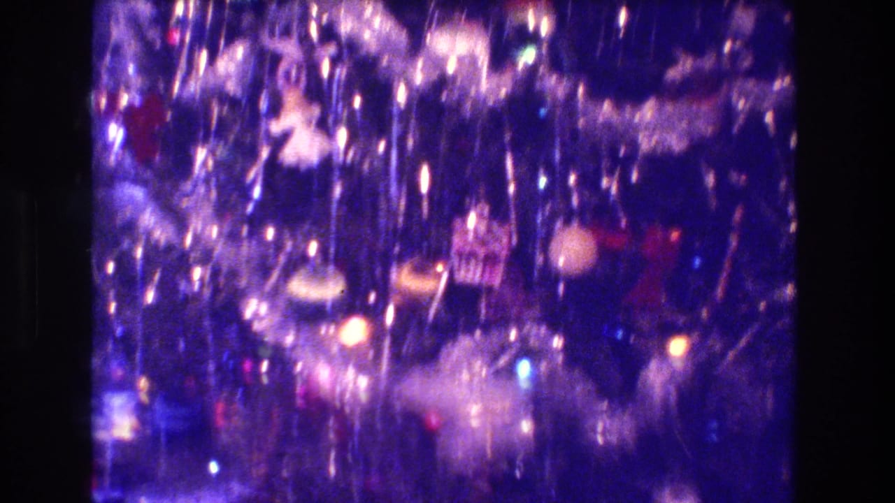 Close view of a tinsel-covered Christmas tree with glowing colored lights.