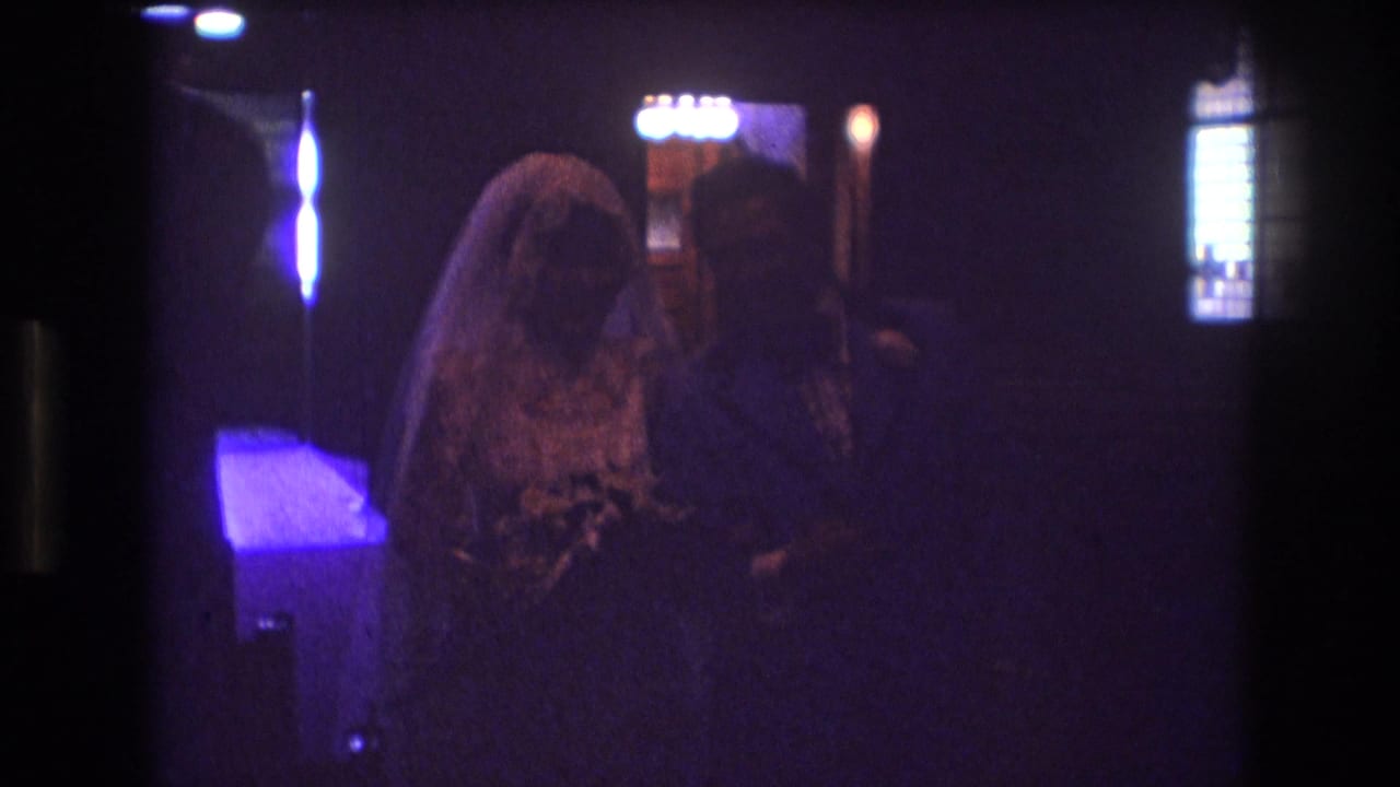 Bride and groom continue down the aisle in a dark church interior.