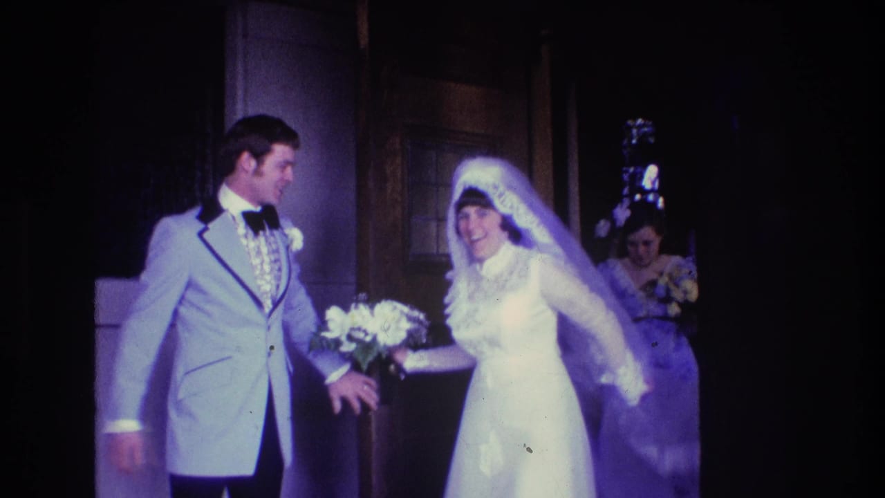 Bride and groom stand near a doorway with a bridesmaid behind them.