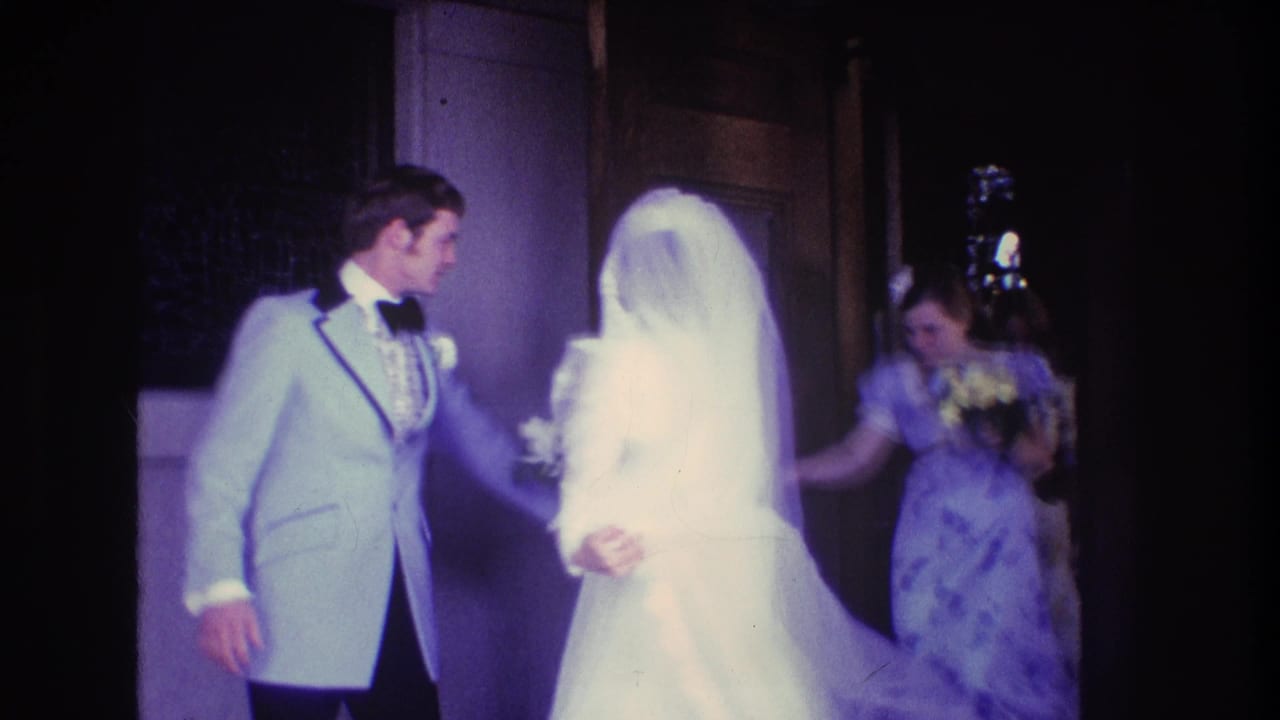 Groom turns toward the veiled bride as a bridesmaid follows behind.
