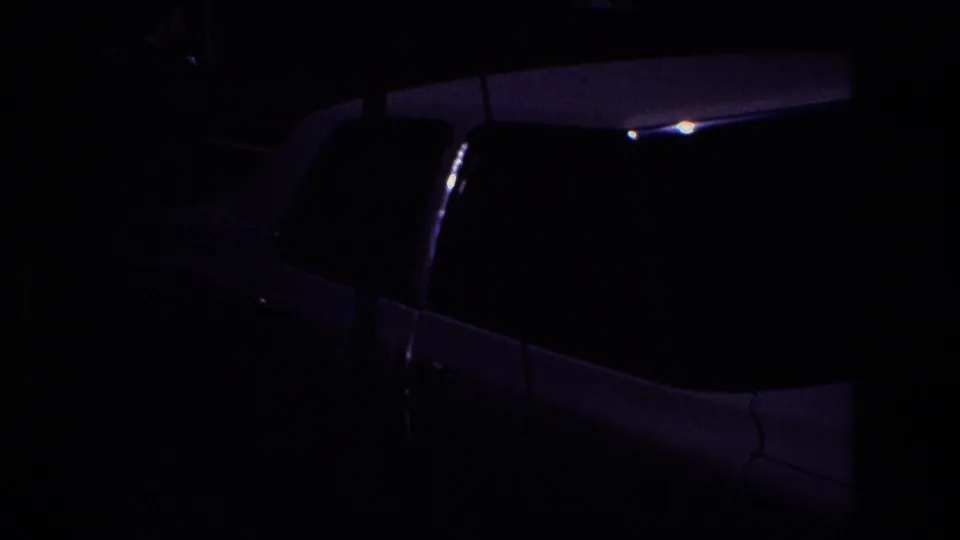 A dark nighttime shot shows the side and roofline of a white limousine or large wedding car, with most details obscured by low exposure.
