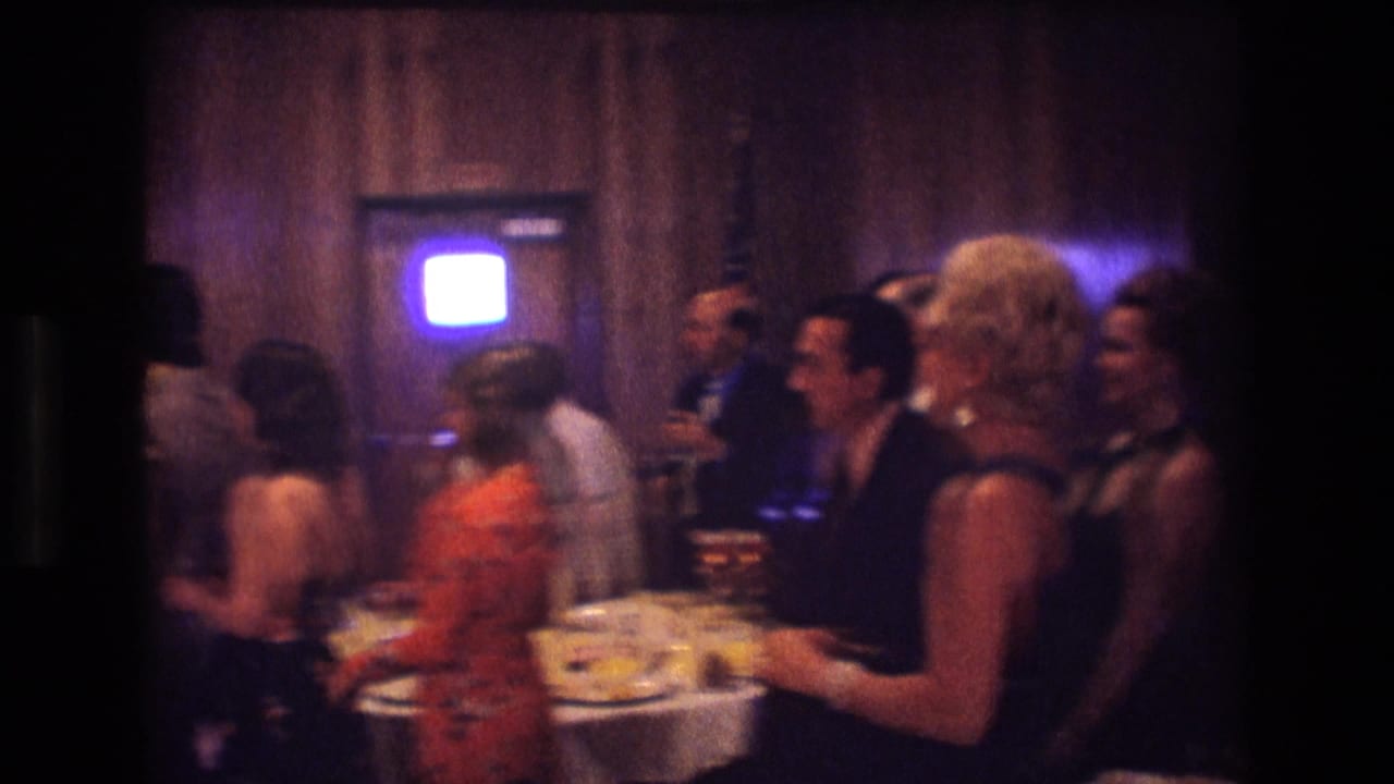Guests in formal clothing gather near a buffet table in a wood-paneled room.