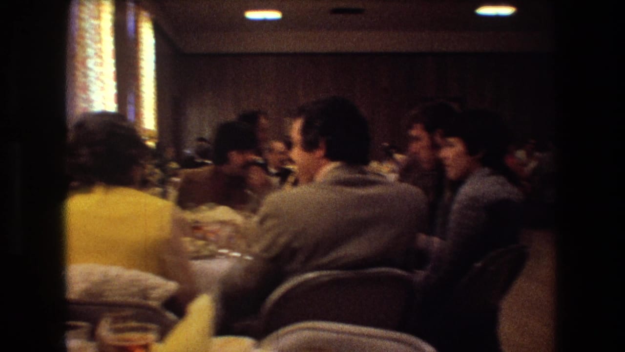 Guests continue eating and talking at a crowded wedding reception table.