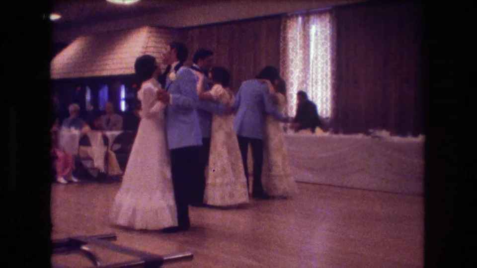 A 1974 Boston wedding reception frame shows a couple dancing in the foreground while another pair dances near the back of the wooden floor.