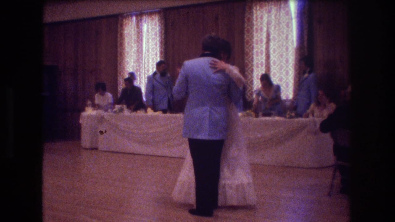 Bride and groom slow dancing in front of seated wedding guests at a reception.