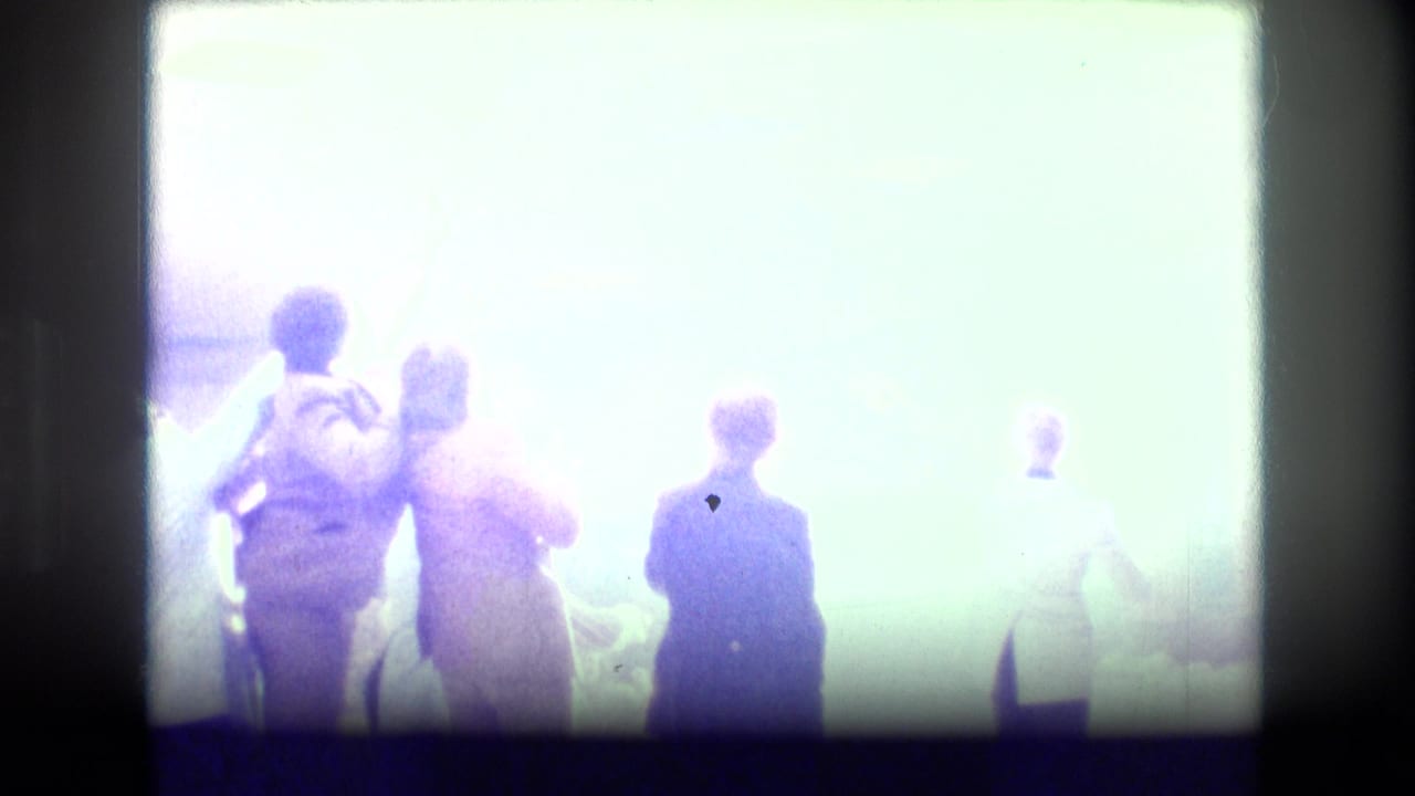Backlit party guests standing near a bright doorway or window in an indoor room.