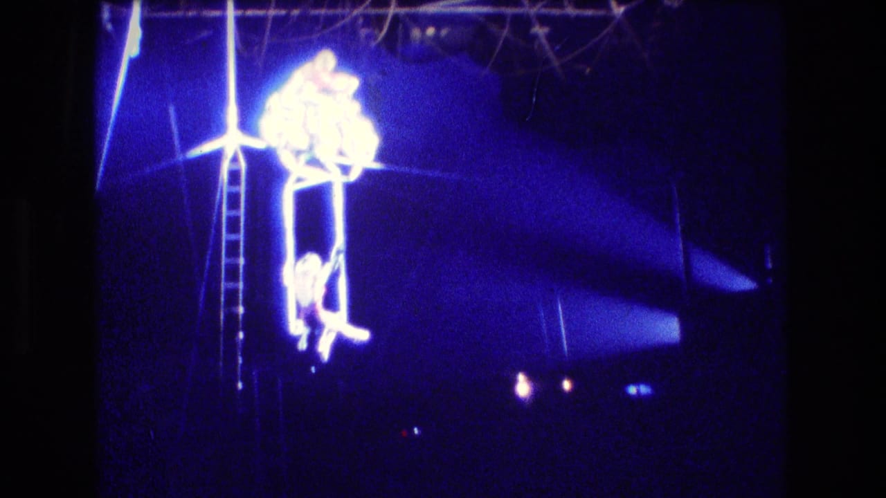 Aerial acrobats on a high rig under intense blue stage lighting.