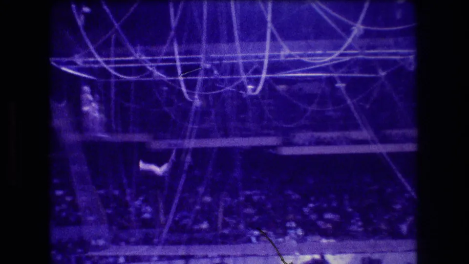 1974 Boston 8mm frame showing dense circus rigging, a safety net, audience seating, and a partially visible trapeze performer near the lower left edge.