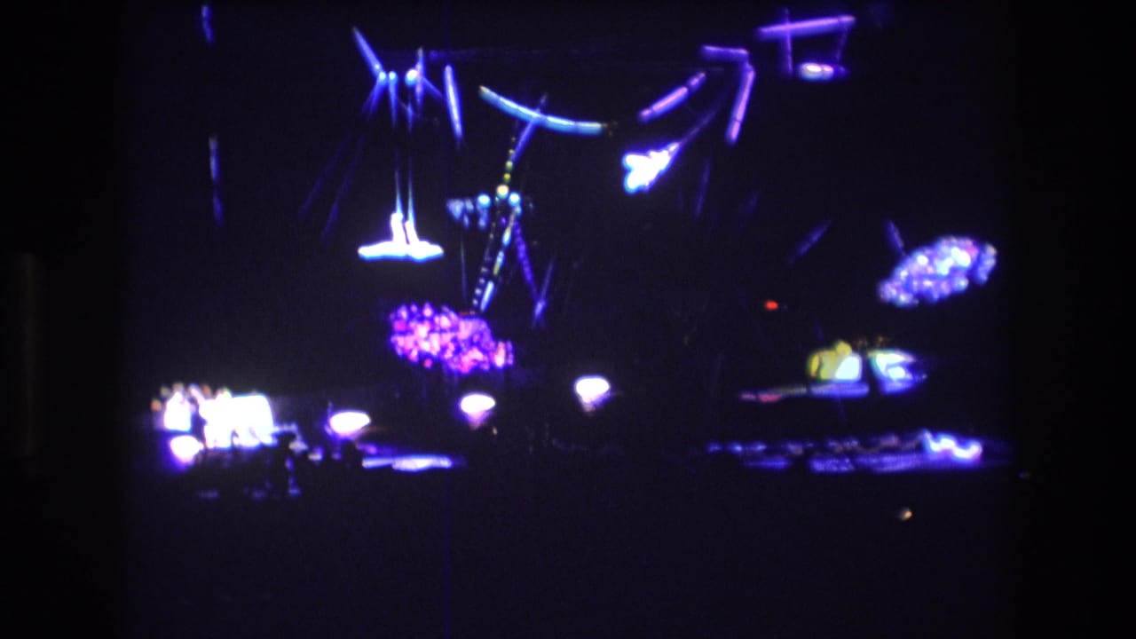 Aerial rigging and bright stage lights above a dark performance area.