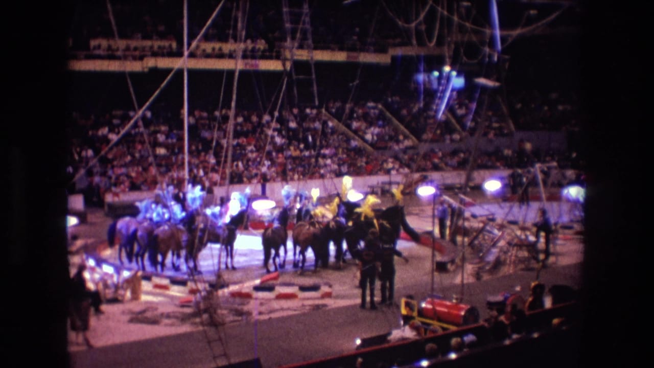 1974 Boston 8mm frame showing a circus horse act in the center ring, with riders under spotlights and a large audience in the background.