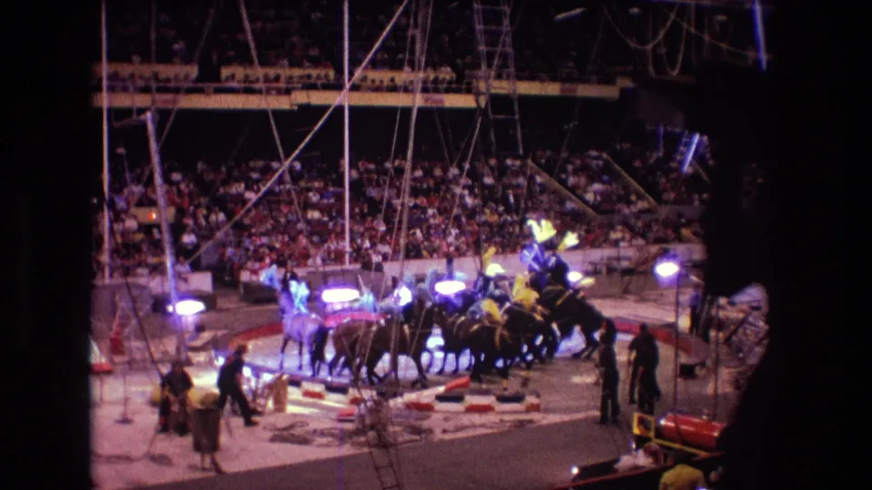 1974 Boston circus frame showing a clustered horse act in the center ring, with performers, attendants, spotlights, rigging, and spectators in the arena background.