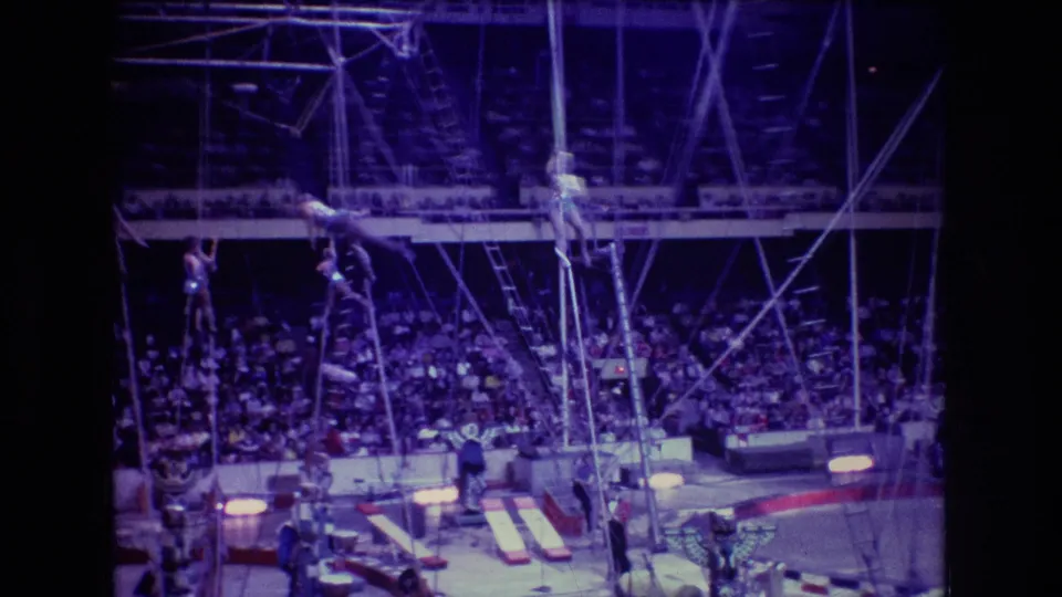 Near the end of the clip, aerial performers are suspended across the arena rigging above mats and equipment, with the seated Boston audience visible in the background.