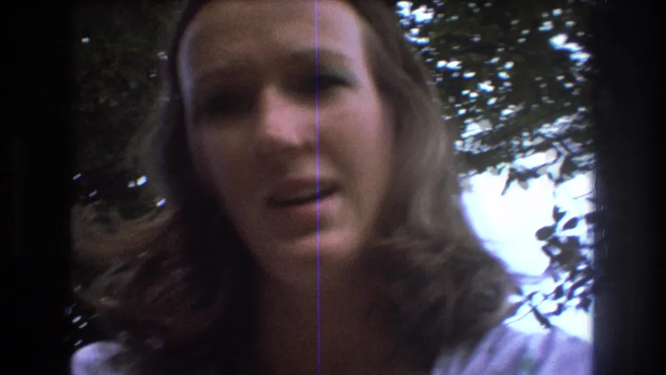 A soft, close handheld 8mm view shows the young woman's face beneath leafy branches during the Baxter, Maine outing.