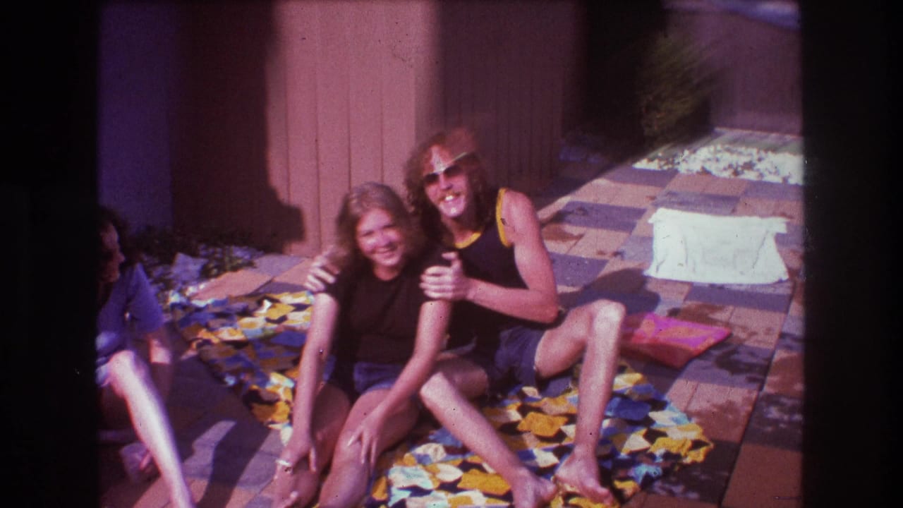 A seated woman and man smile while another person is partly visible at the edge.