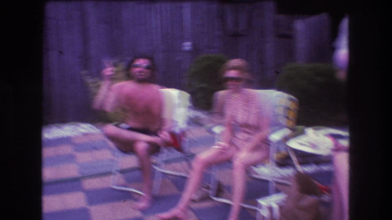 Two adults seated on patio chairs with another person partly visible at the edge.