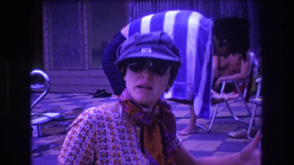 The final frame shows the woman seated foreground in sunglasses, cap, and scarf, with a blue-and-white striped towel and shirtless seated man behind her in the 1975 Boston poolside scene.