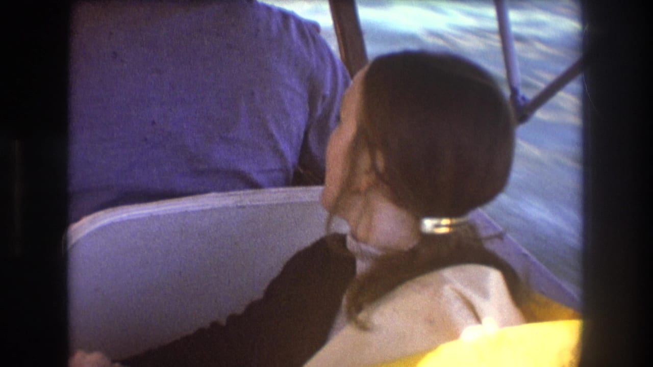 A young brunette woman sits in a small motorboat near Boston, wearing a light life vest as blue water moves past the boat.
