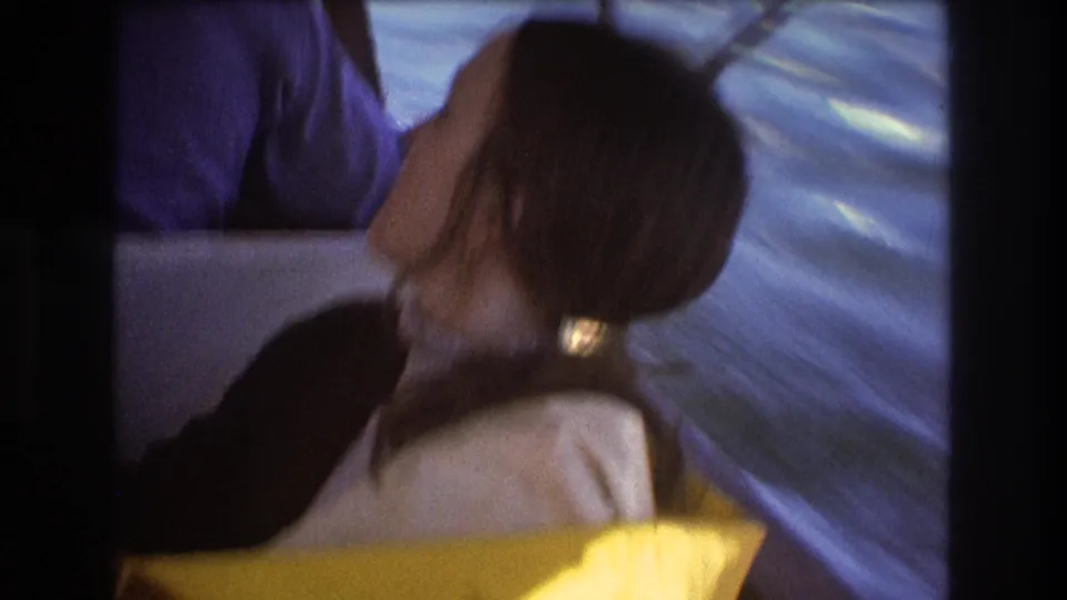The woman remains seated in the motorboat with her head turned, with rippling water and boat hardware visible around her.