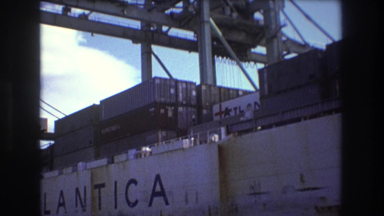 1975 Boston port frame with the ATLANTICA name visible on a docked freight ship below stacked containers and industrial crane structures.