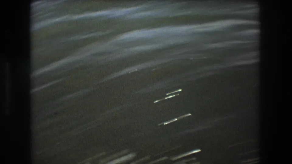 1975 Boston 8mm frame showing rippled green-blue water with bright streaks and dark boat-side borders on both sides.