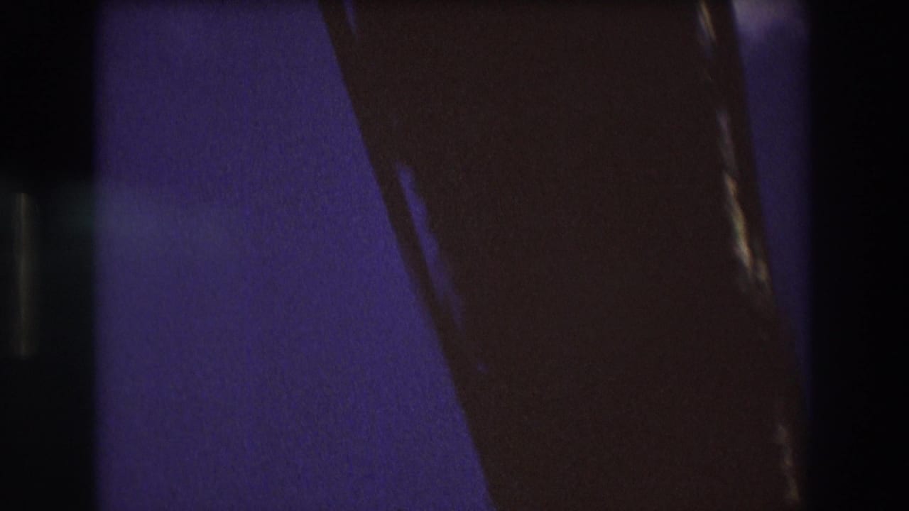 Dark 8mm frame from the Boston 1975 boat sequence, with heavy shadow, grain, and partial structural or film-edge shapes obscuring the view.
