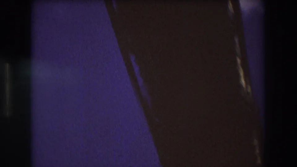 Dark 8mm frame from the Boston 1975 boat sequence, with heavy shadow, grain, and partial structural or film-edge shapes obscuring the view.