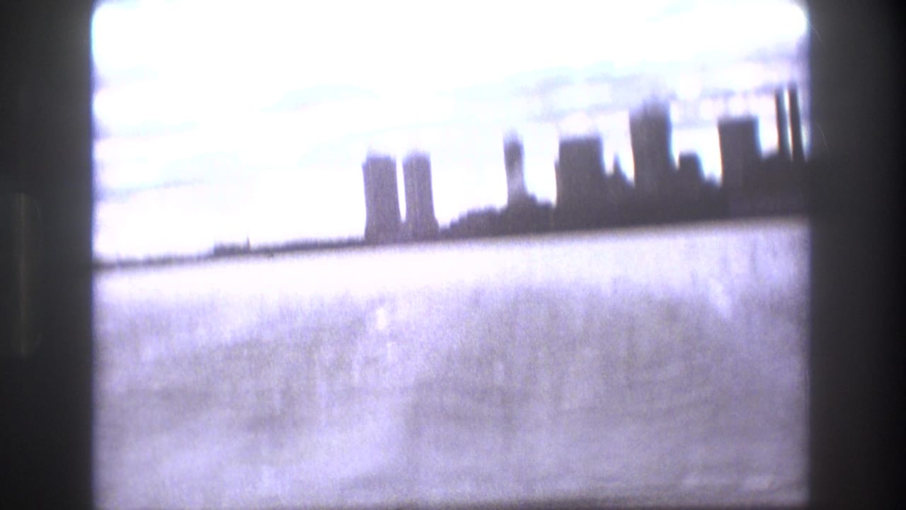 Soft 1975 Boston waterfront view from a boat, showing water in the foreground, a distant skyline, and a bright cloudy sky.