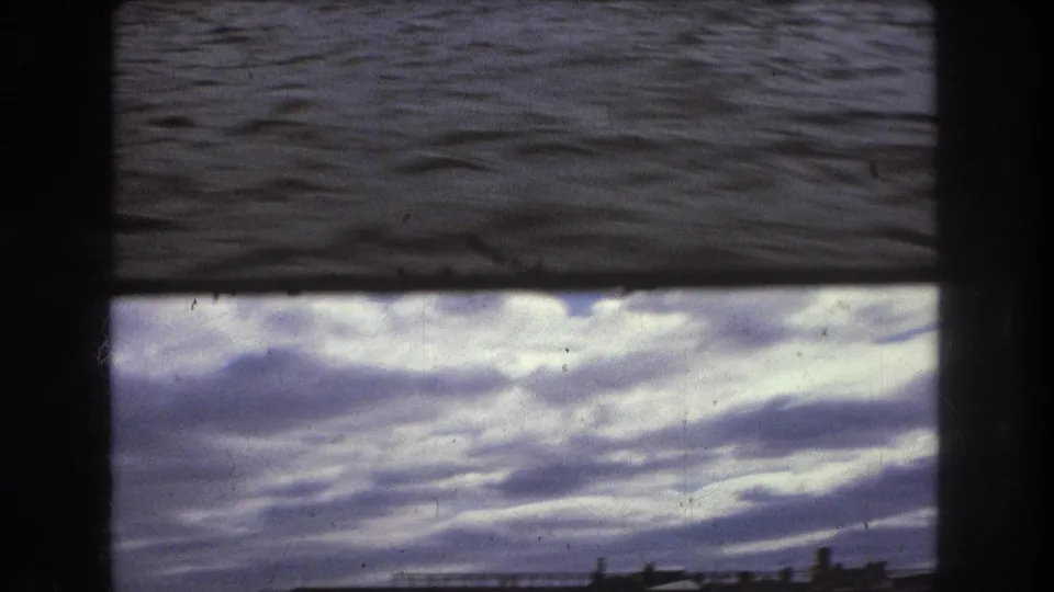 Close view of rippling harbor water in dark 8mm exposure, framed by the physical edges of the film scan.