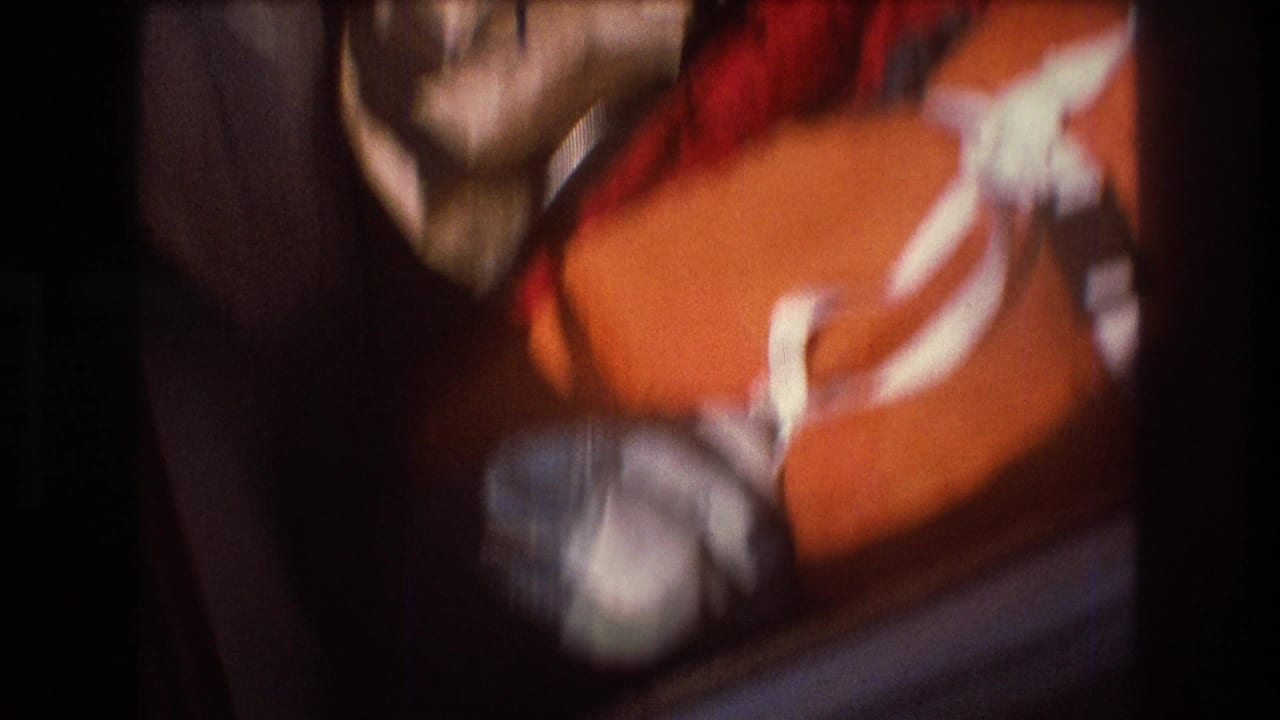 Close 1975 8mm frame of an orange duffel bag with white straps packed tightly with other soft luggage, likely before or during a boating trip near Boston.