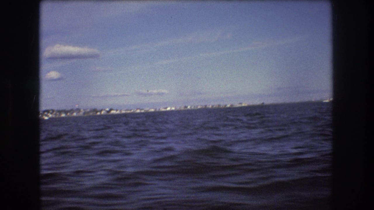 The final frame shows rippled harbor water, a low strip of distant buildings, and scattered clouds beneath the 8mm frame borders.