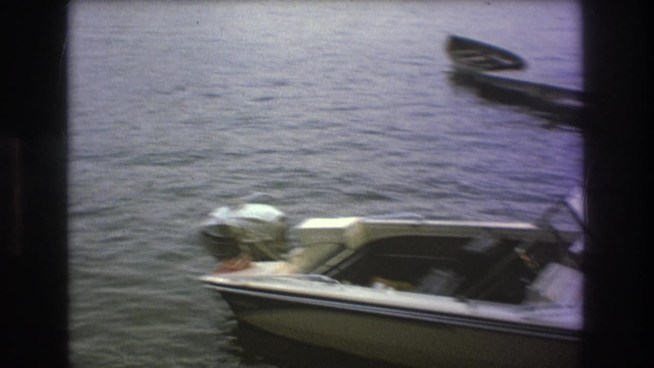 White motorboat floating near docked boats on calm lake water.