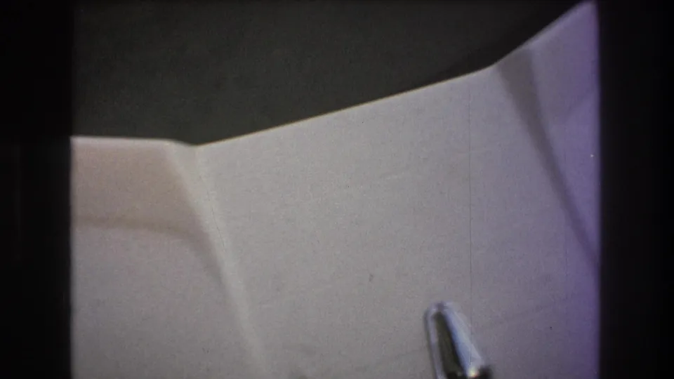 Soft 8mm frame from a 1975 Boston-area boating clip showing a white molded cabin surface, a small metal handle, and dark film-edge shadows.