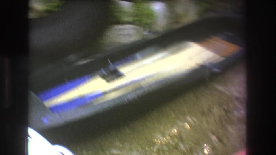 A motion-blurred 8mm frame shows a striped water ski or boat gear near wet ground and greenery as the camera moves close to the equipment.