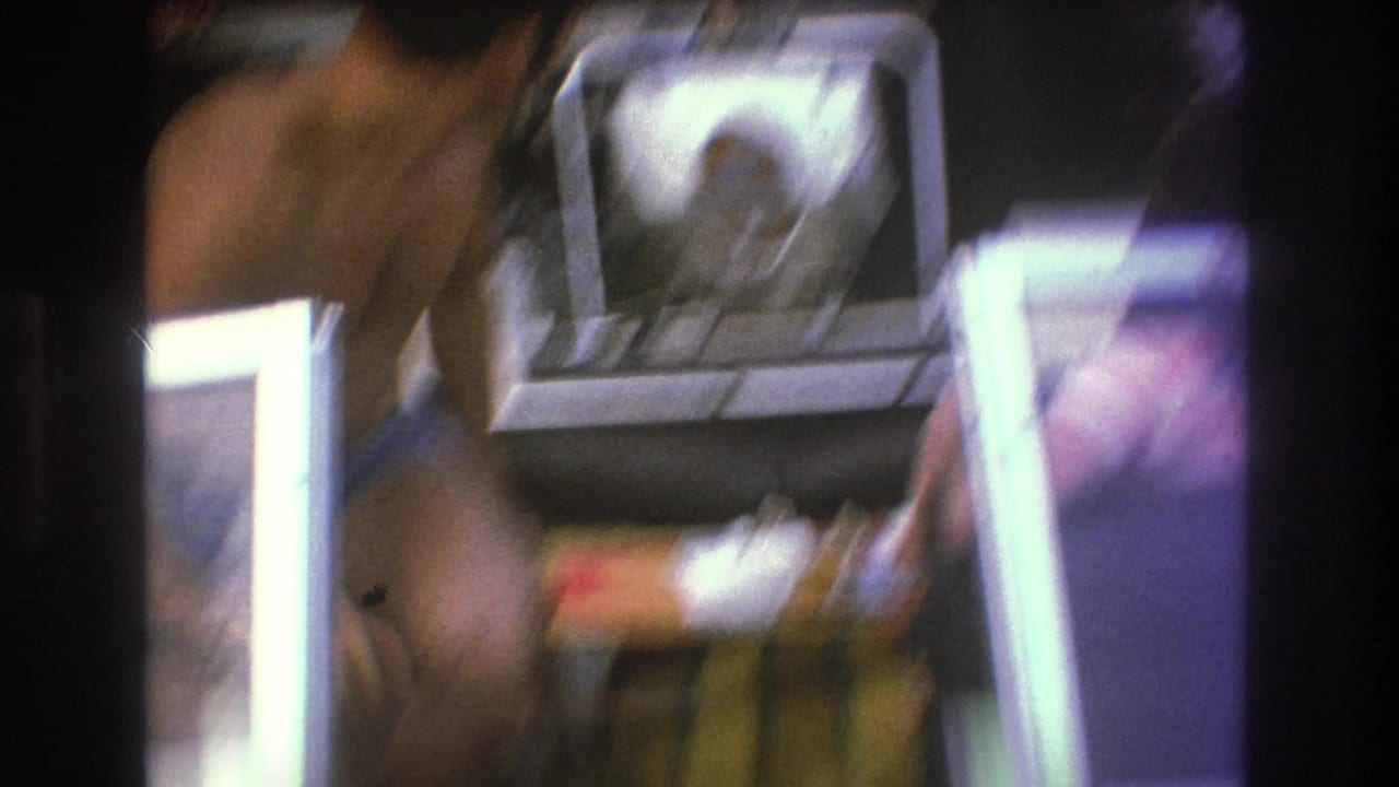 Soft, blurred 1975 Boston 8mm frame showing adults on a small motorboat with a white outboard engine and dark film-frame borders.