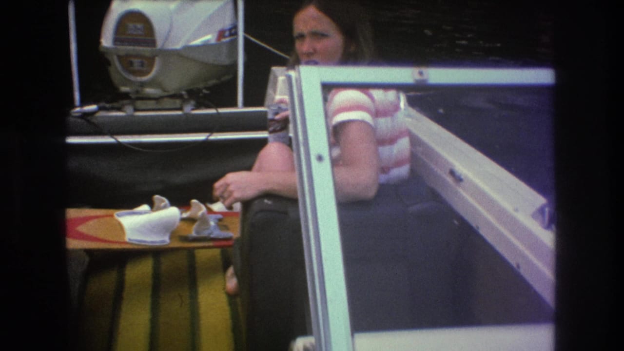 Woman sitting in a motorboat with an outboard motor behind her.