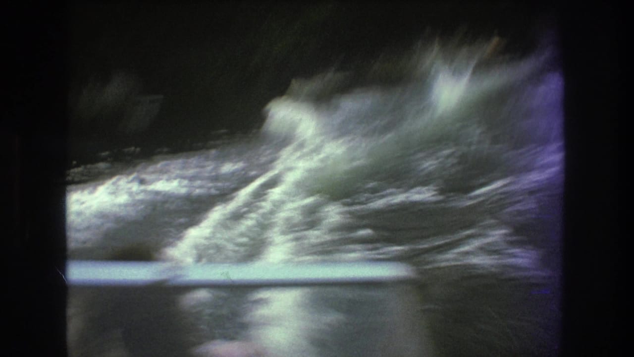 A burst of spray and wake fills the 1975 8mm lake frame, suggesting the skier is struggling or has just dropped into the water.