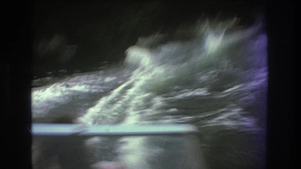 A burst of spray and wake fills the 1975 8mm lake frame, suggesting the skier is struggling or has just dropped into the water.