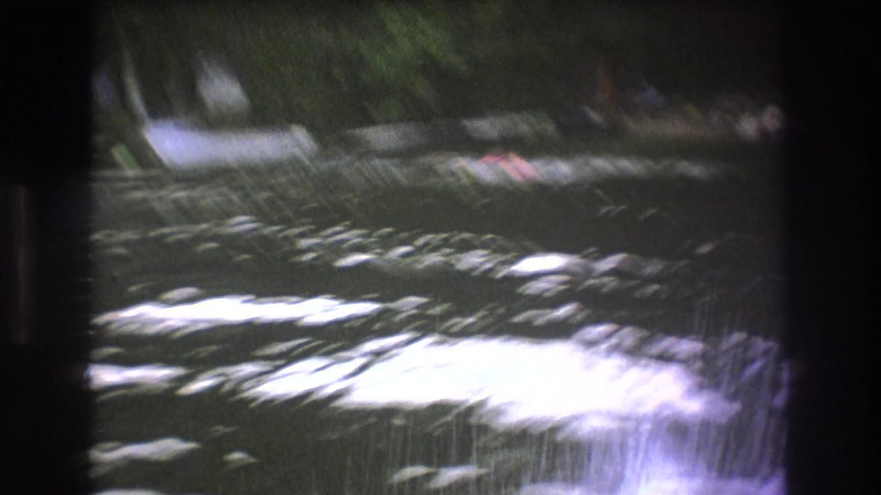 Blurred lake surface with boats near the far shoreline.