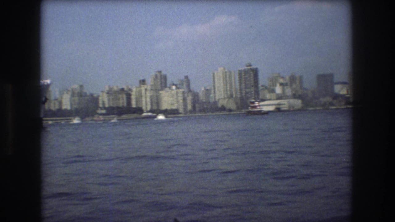1975 8mm view of the Boston waterfront skyline, with boats on the water and dark vertical frame borders from the film scan.