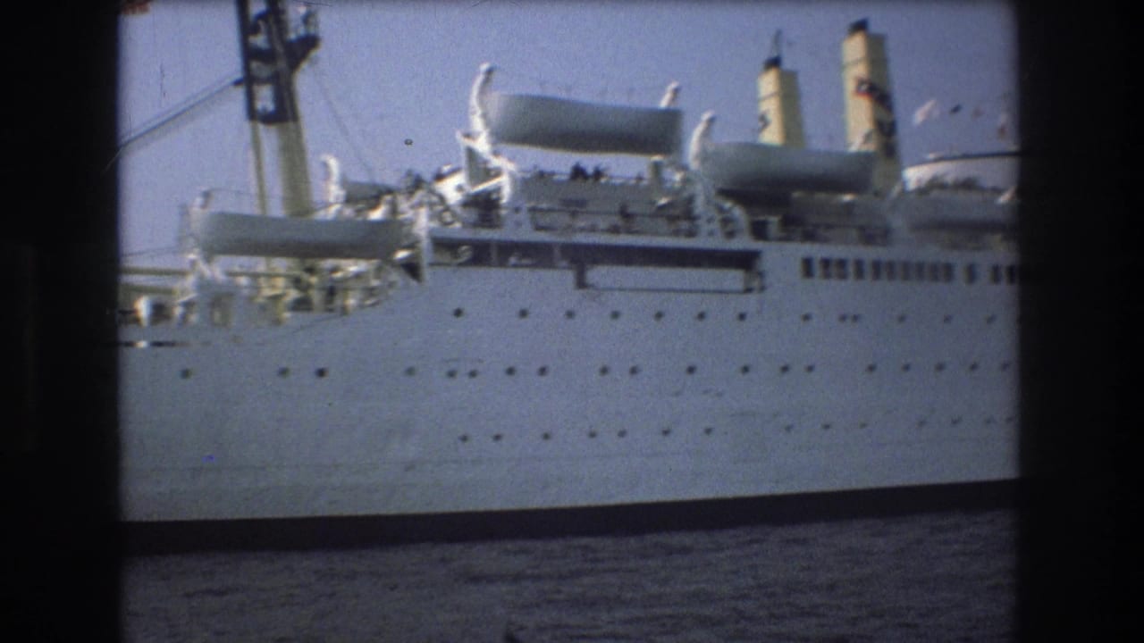 Close 8mm view of the large white vessel in Boston harbor, with hull portholes, upper deck equipment, smokestacks, and rigging visible.