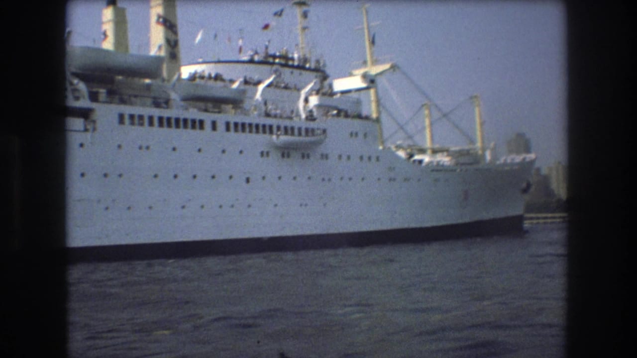 A large white passenger ship with decks, lifeboats, and cranes appears on Boston harbor water in the supplied 1975 home-movie clip.