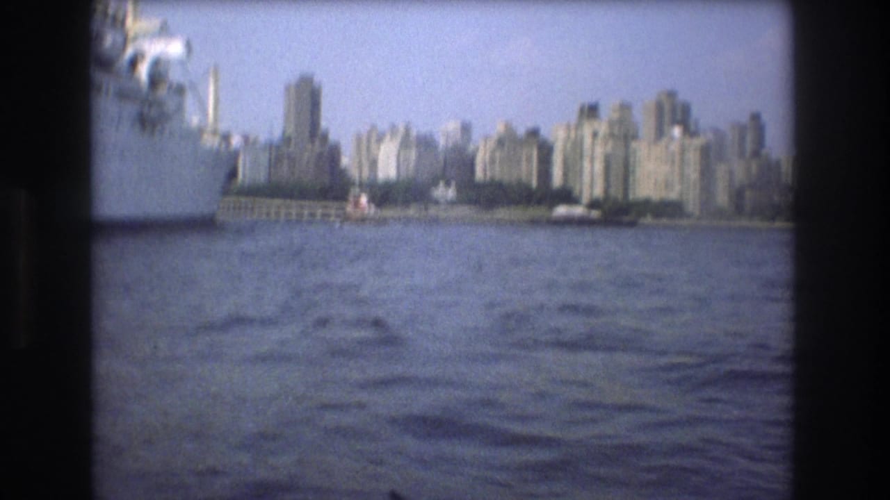 Distant high-rise skyline seen over open water from a boat.