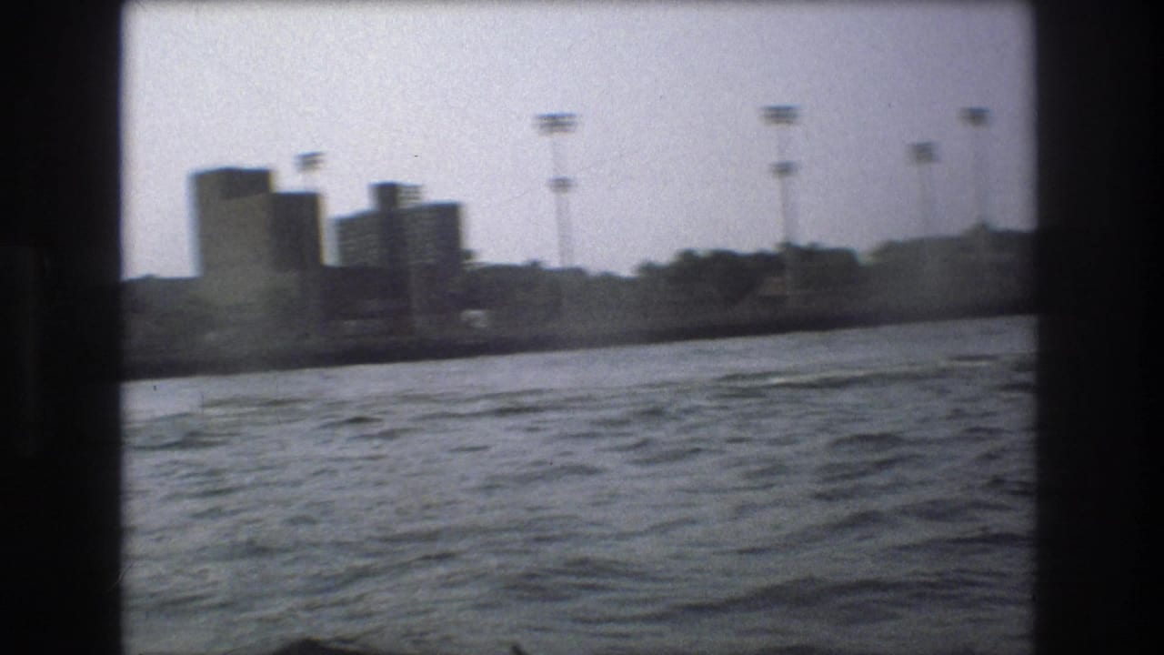 Distant waterfront buildings and tall poles across choppy water.